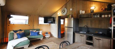 Un espacio habitable acogedor y funcional con sofá, mesa de comedor y kitchenette.