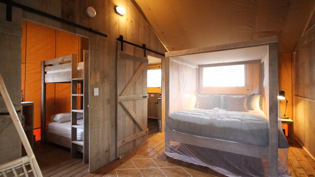 Een rustieke slaapkamer met een hemelbed, een bedstede en een houten garderobe.