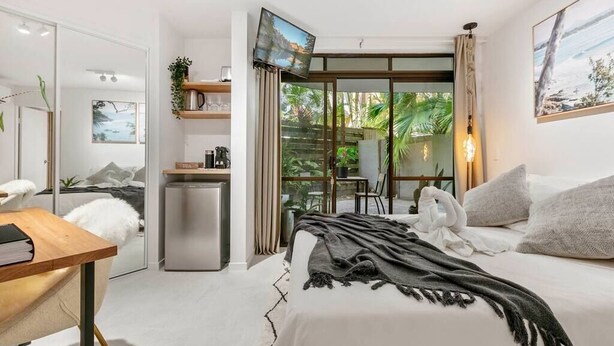 Ein Hotelzimmer mit Bett, Schreibtisch, Fernseher und Blick ins Freie.