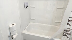 A bathroom with a bathtub, toilet, and a towel rack. - Queen Bedroom In Saco (Saco)