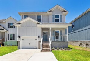 A two-story residential house with a front porch, a garage, and a well-maintained lawn. - Serenity in Perdido Key| 2 King Suites| Game Room| Fire table| Close to Beaches, Shops & Restaurants (Pensacola)