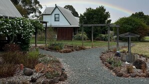A gravel driveway leading to a house with a covered porch and a wooden fence. - Murray River Spa Retreat (Echuca)