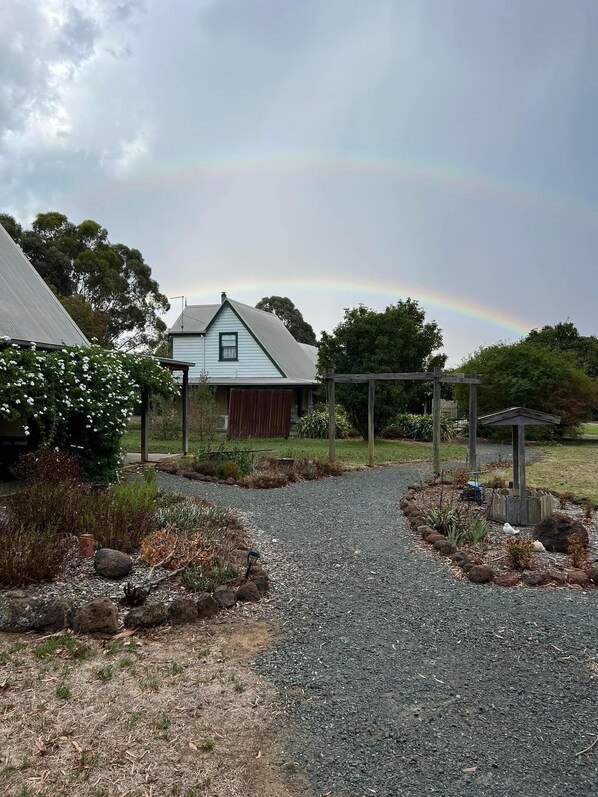 A gravel driveway leading to a house with a covered porch and a wooden fence. - Murray River Spa Retreat (Echuca)