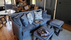 A cozy living room with a blue sofa, a coffee table, and a bookshelf filled with books and decorative items. - Murray River Spa Retreat (Echuca)
