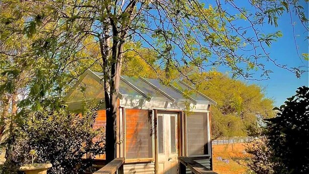 A small house with a wooden deck and a pond in the foreground. - Murray River Spa Retreat (Echuca)