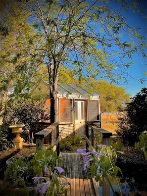 A small house with a wooden deck and a pond in the foreground. - Murray River Spa Retreat (Echuca)