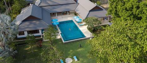 Una casa grande con piscina, varias habitaciones y un jardín bien cuidado.