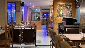 Interior de restaurante con mobiliario de madera, una zona de bar y una barra.
