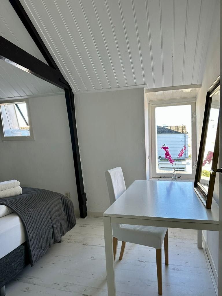 Un dormitorio con cama, una mesa y una ventana.