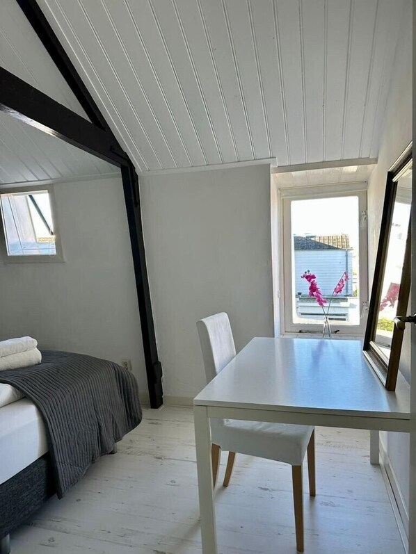 Un dormitorio con cama, una mesa y una ventana.
