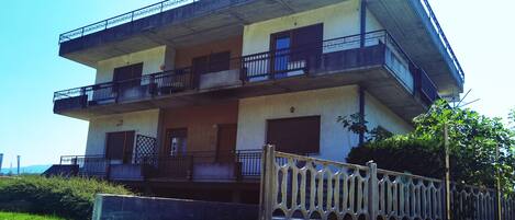 A multi-story building with balconies, a gated entrance, and a concrete facade.