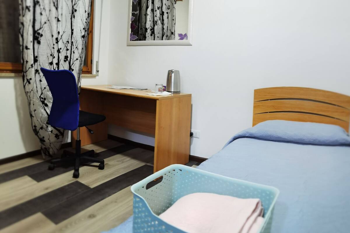 Une chambre à coucher avec un lit, un bureau, une chaise et un panier.