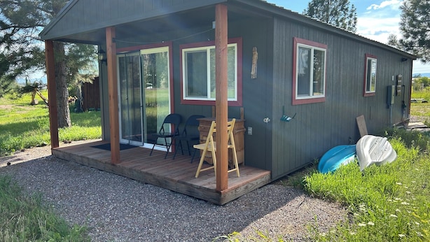 A small cabin with a covered porch, sliding glass doors, and a gravel driveway. - Dreamcatcher Bungalow 20min to W.Glacier, between Glacier&Airport (Columbia Falls)