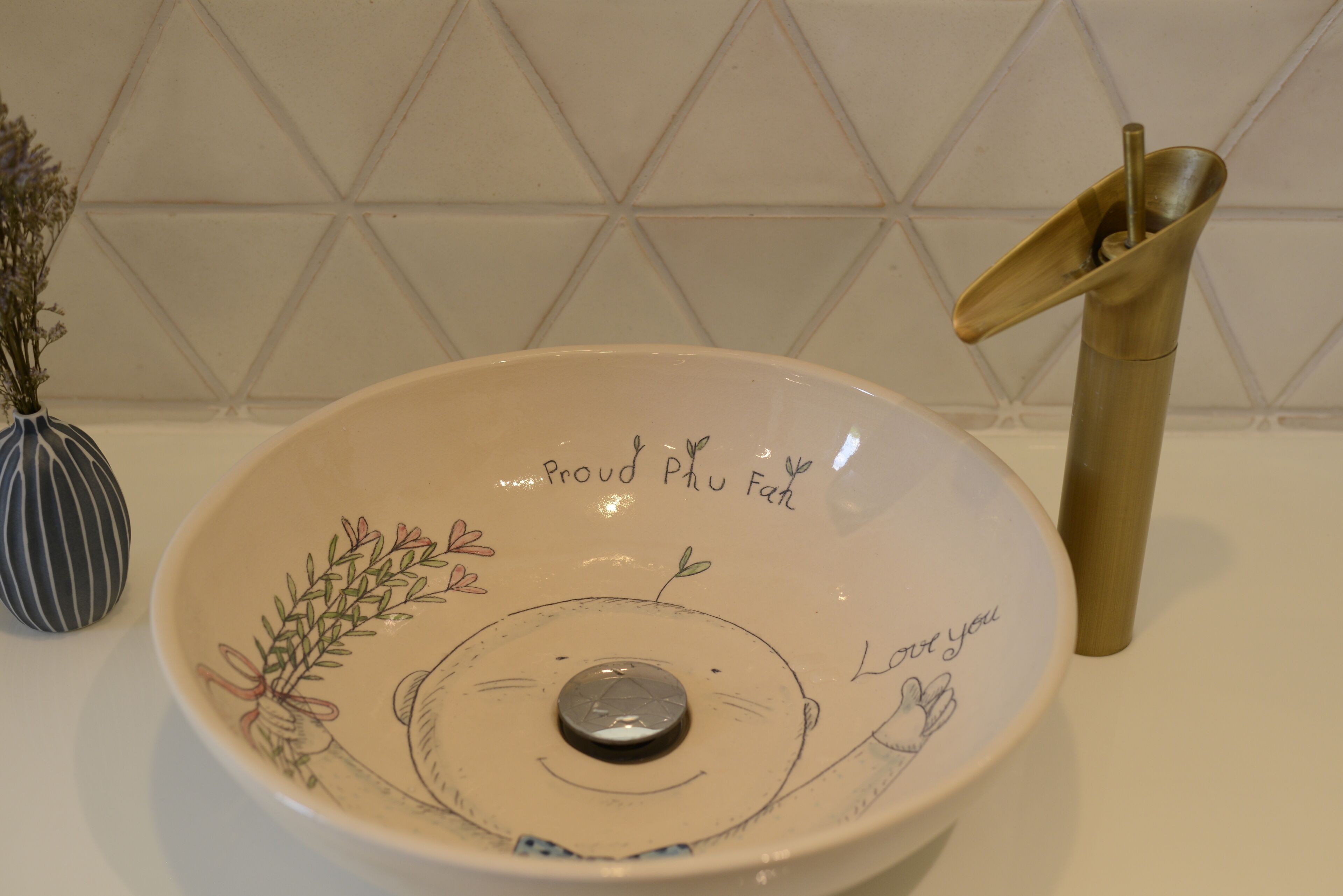 A ceramic basin with a floral design and text, placed on a white countertop.