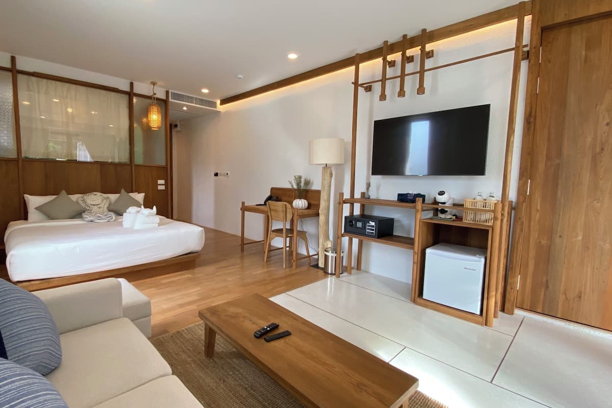 Een moderne hotelkamer met een bed, een bank, een bureau met een computer, een televisie en een minibars.