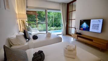 A hotel room with two beds, a TV, and a view of greenery outside.