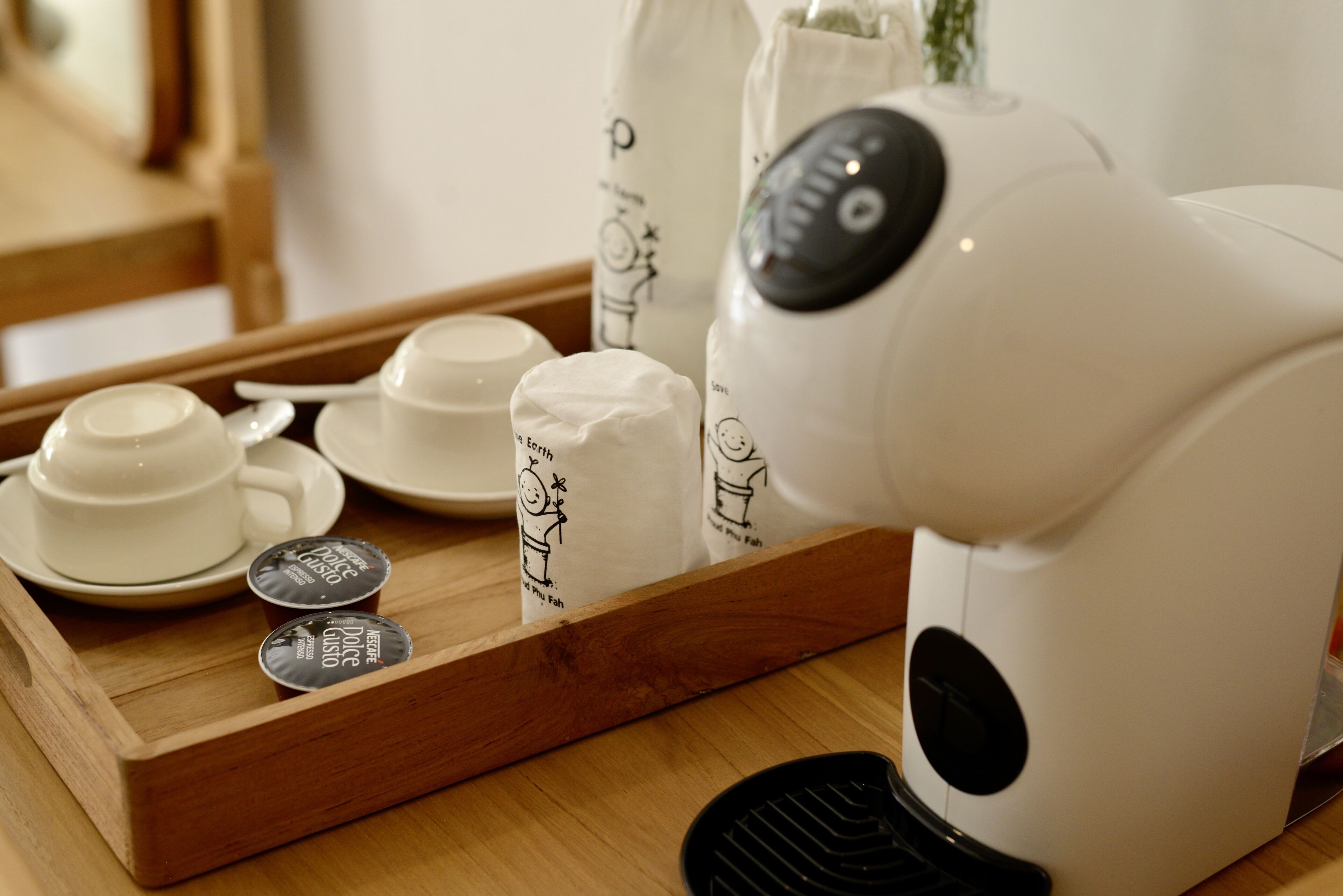 Una cafetera, tazas y cápsulas de café Dolce Gusto sobre una bandeja.
