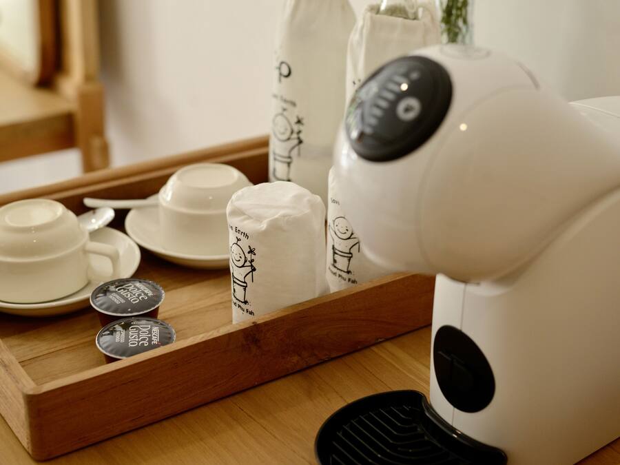 Una cafetera, tazas y cápsulas de café Dolce Gusto sobre una bandeja.
