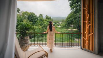 A balcony with a view of lush greenery and distant hills.