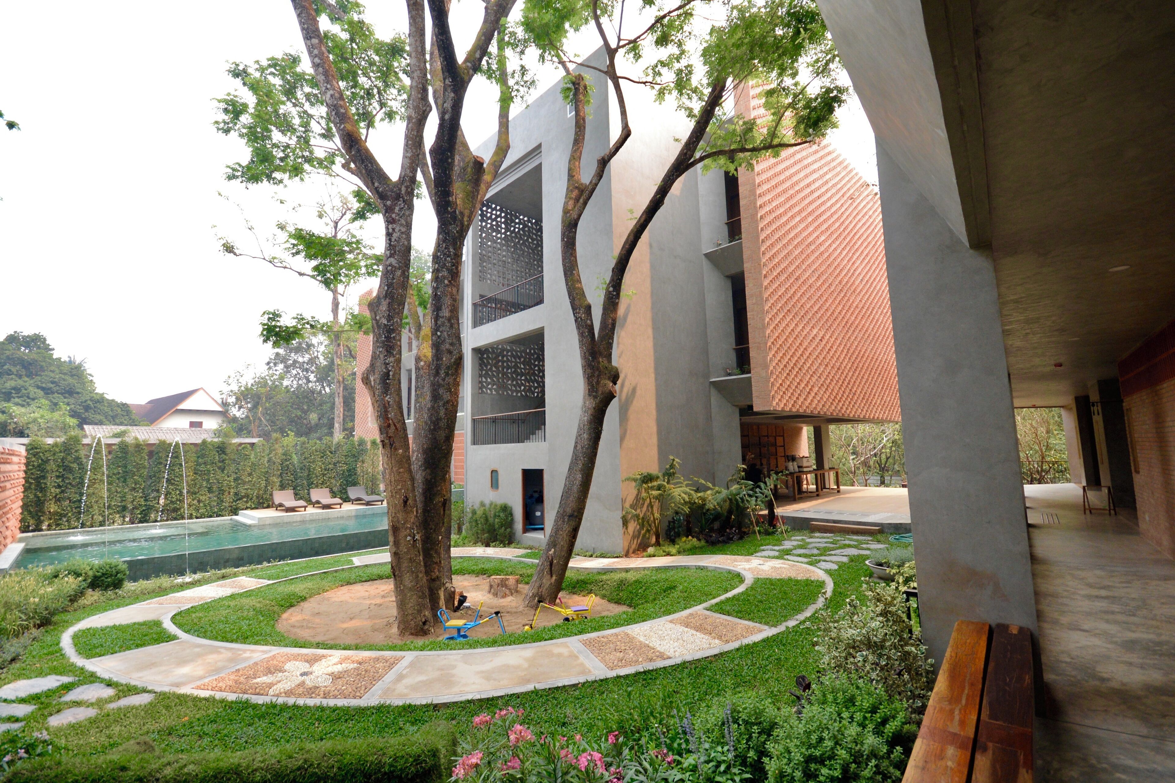 A modern building with a swimming pool, surrounded by greenery and trees.