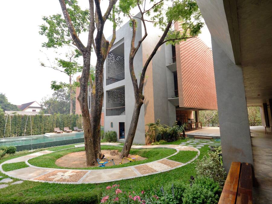 A modern building with a swimming pool, surrounded by greenery and trees.