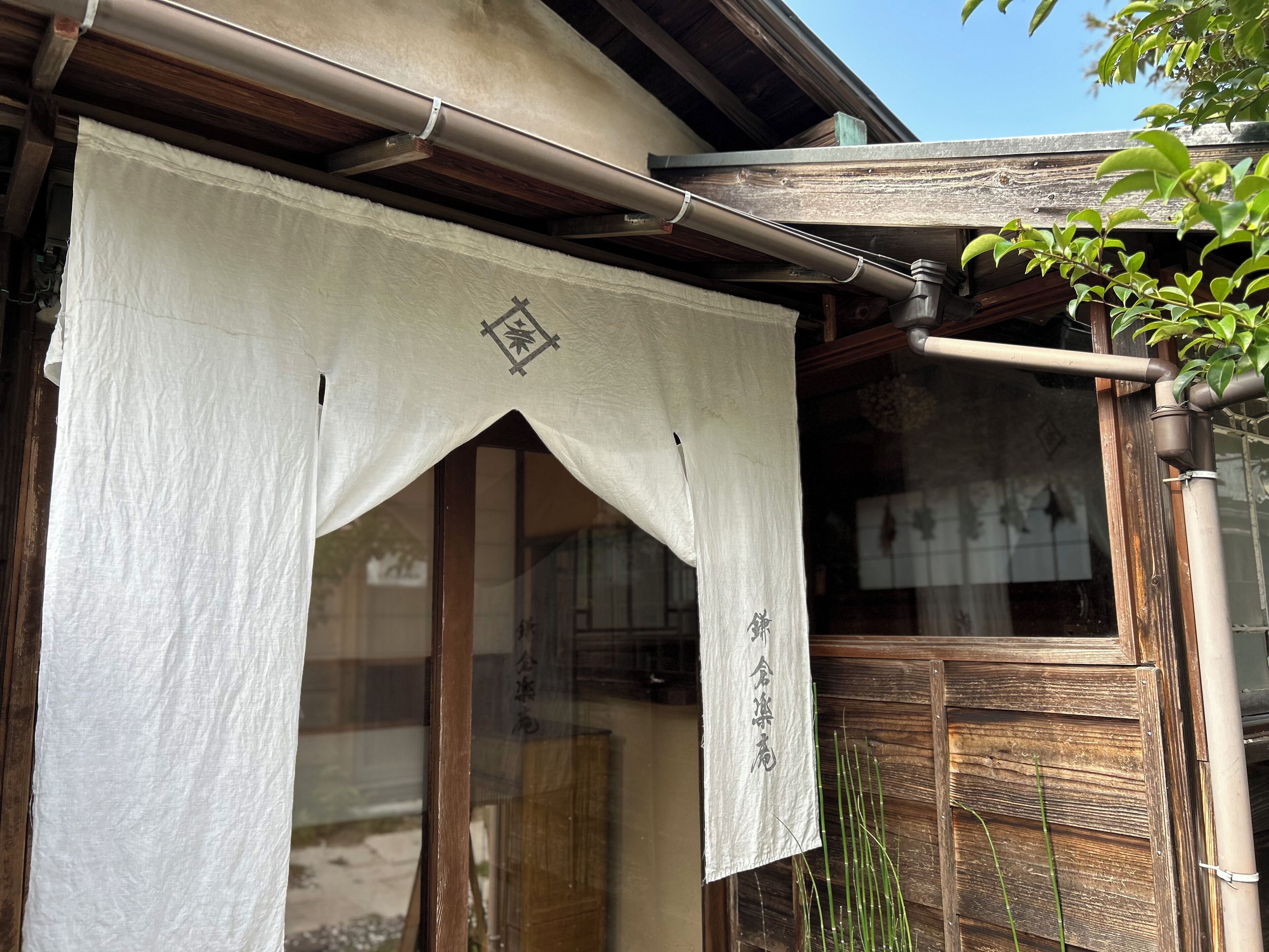 Un edificio japonés tradicional con fachada de madera, un panel corredizo shoji y un pequeño jardín con bambú.