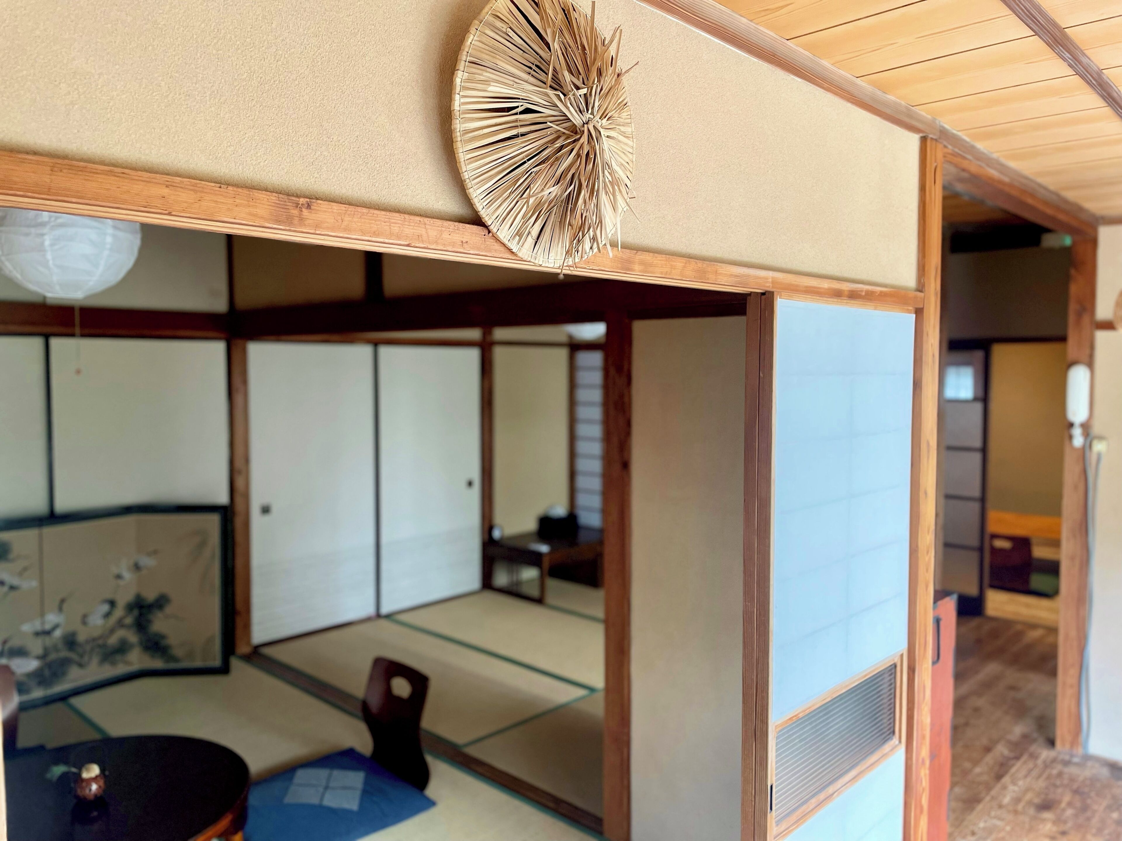 Una habitación japonesa tradicional con suelo de tatami, puerta corredera shoji y una baja mesa de madera con un tapete azul.