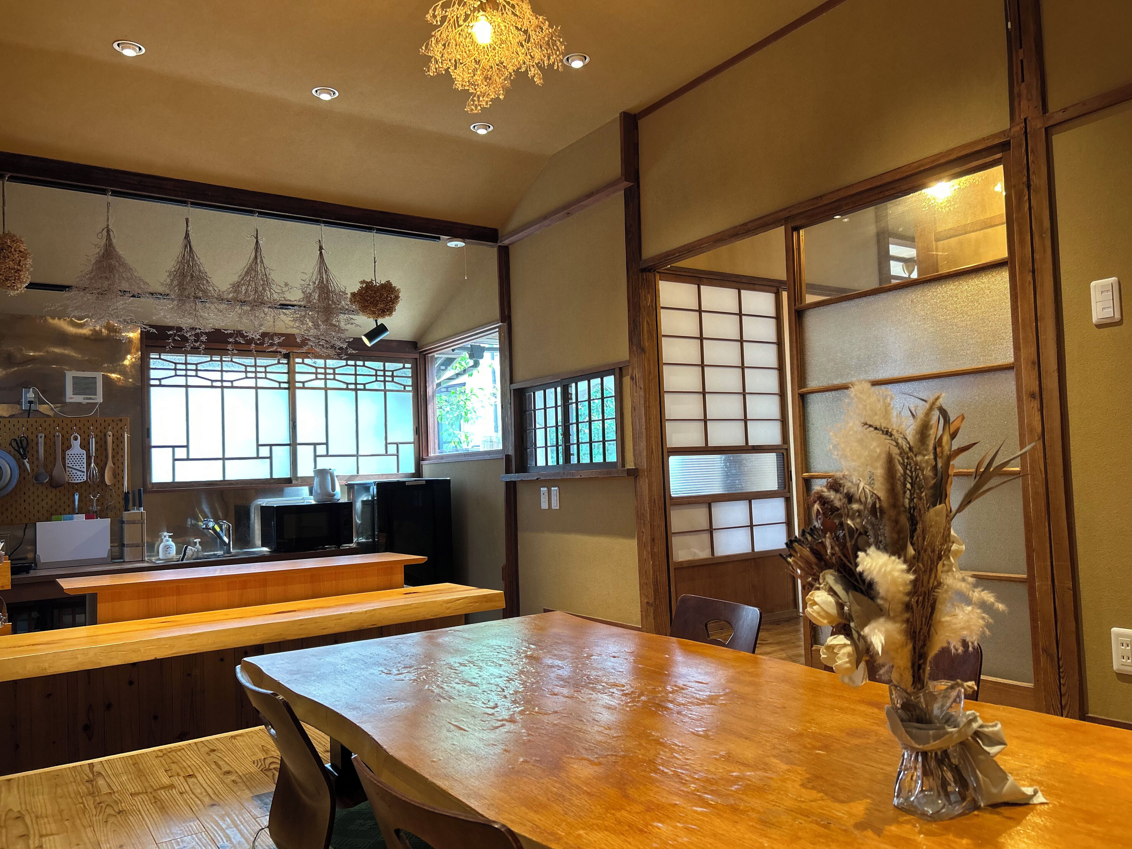 A traditional Japanese-style dining area with wooden furniture, a large table, and a decorative vase.