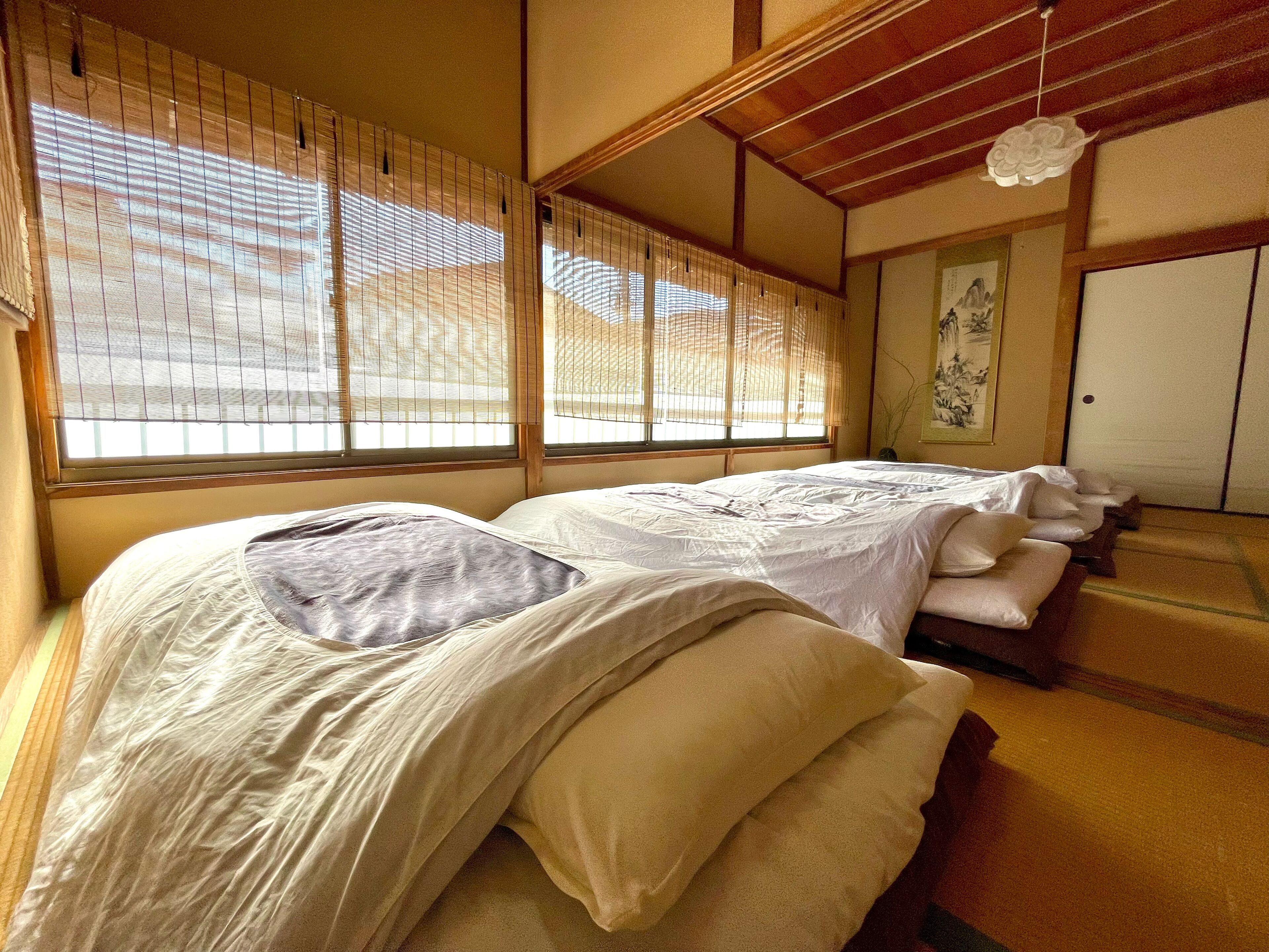 A traditional Japanese-style room with tatami flooring, shoji screens, and a futon bed arrangement.