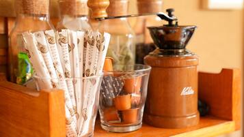 Une étagère en bois avec des bouteilles en verre, un moulin à café et des sachets de sucre.