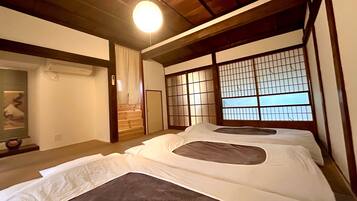 A traditional Japanese-style room with tatami flooring, a shoji screen, and a futon bed.