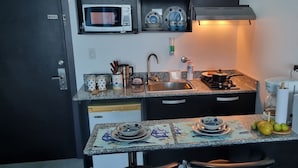 Cocina compacta con microondas, pileta, cocina y diversos utensilios.
