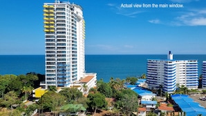 Un hotel de altura con varios balcones, vistas al mar y vegetación circundante.