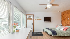 Una habitación moderna con cama, escritorio y ventilador de techo.