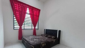 Quarto com cama, janela com persianas e cortina vermelha.