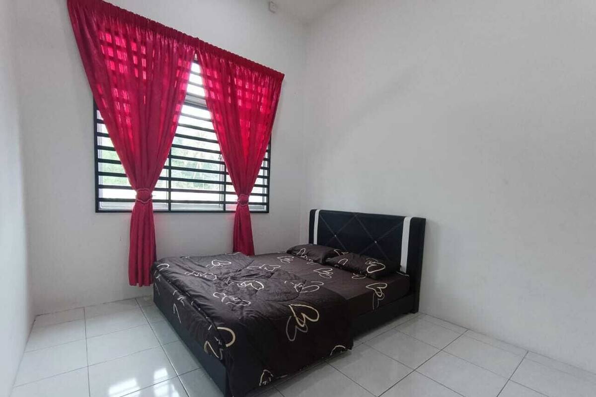 Ein Schlafzimmer mit einem Bett, einem Fenster mit Jalousien und einem roten Vorhang.