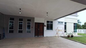 Um edifício moderno com um amplo pátio, uma porta de madeira e um pequeno jardim com plantas em vasos.