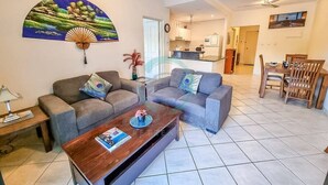 A living room with two grey sofas, a wooden coffee table, and a wall-mounted fan. - ZEN CITY MODERN - 1 BR City Apartment (Larrakeyah)
