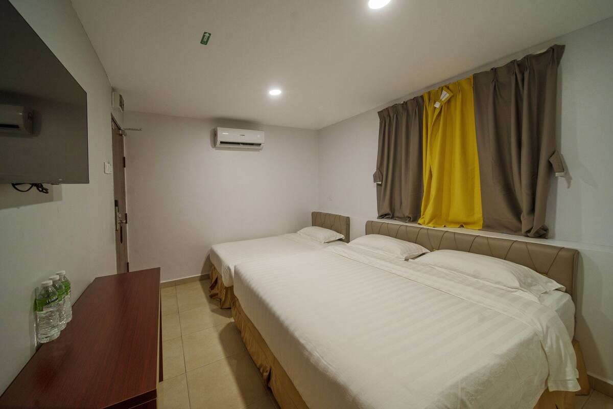 Ein Hotelzimmer mit zwei Betten, einem Holztisch und einem Flachbildfernseher.