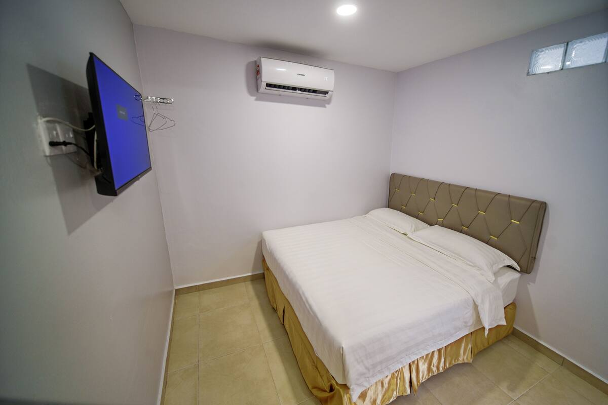 Ein Schlafzimmer mit einem Bett, einer Wand-Klimaanlage und einem Flachbildfernseher an der Wand.