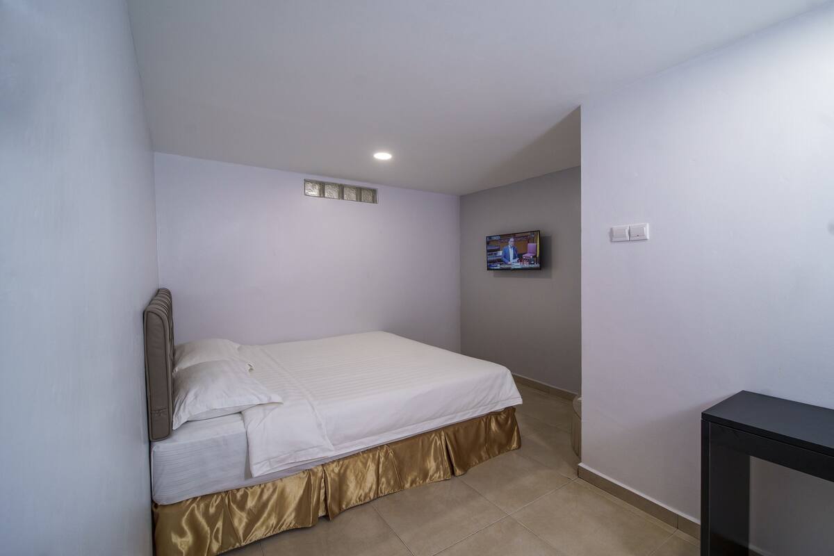 Ein Schlafzimmer mit einem Bett, einem Fernseher an der Wand und einem kleinen Tisch.