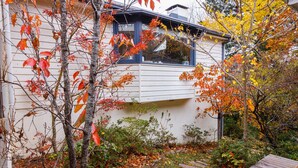 A modern house with a white exterior, a visible window, and a stone pathway leading to the entrance.