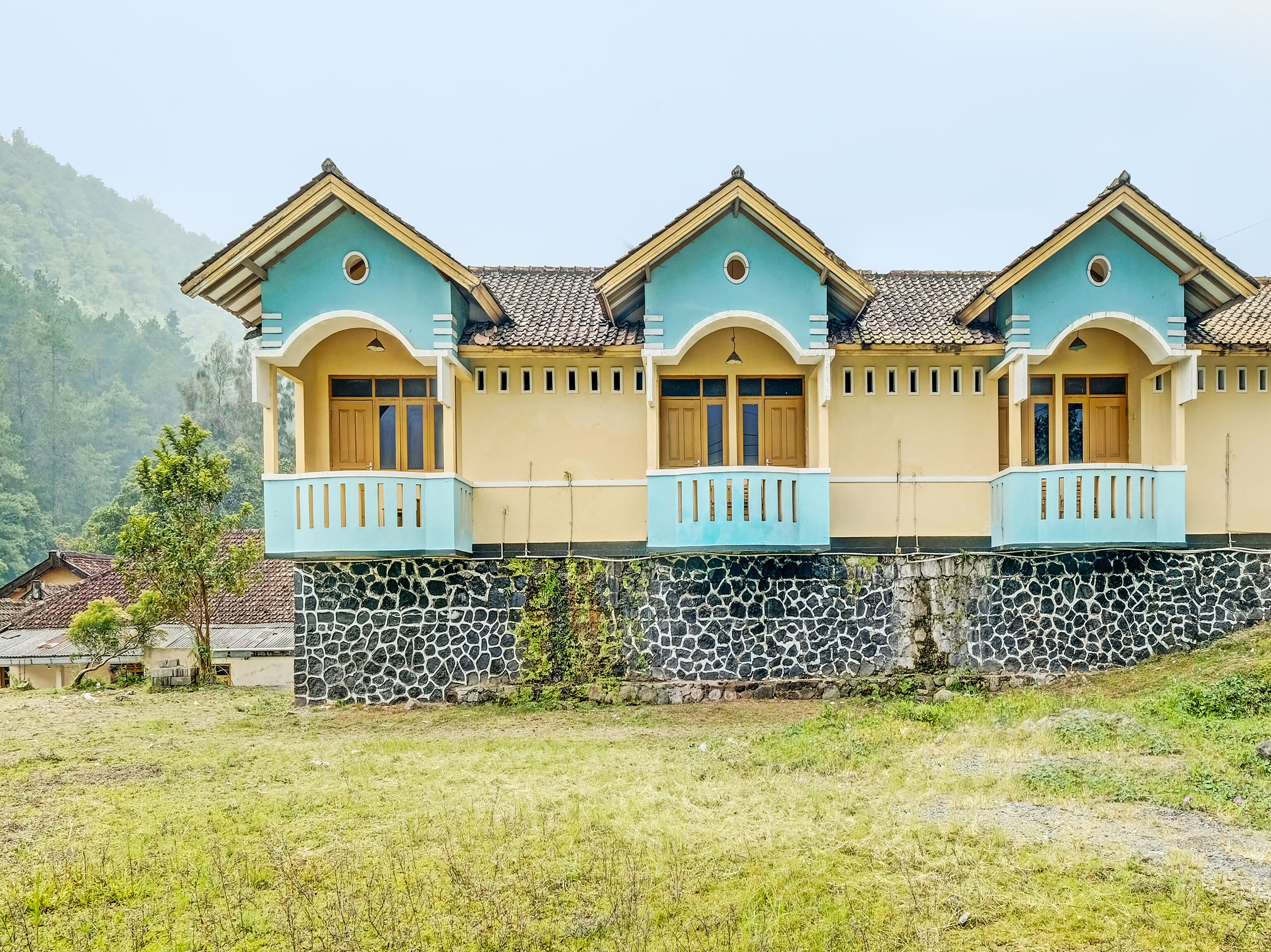 A row of three-story buildings with stone foundations and a light blue and beige color scheme.