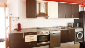 Una cocina moderna con gabinetes marrón oscuro, electrodomésticos de acero inoxidable y techo rojo.