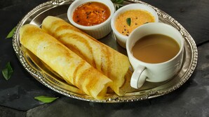 A plate with two rolled crepes, two small bowls of chutney, and a cup of tea. - Covie Gurgaon 42 (Gurugram)