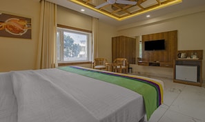 A hotel room with a bed, a desk, a television, and a window. - Treebo Haveli Resort Roots, Bhupatwala Haridwar (Haridwar)