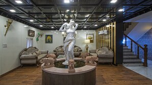 Una sala de estar lujosa con una fuente central, elegantes sofás y una escalera que conduce a un nivel superior.