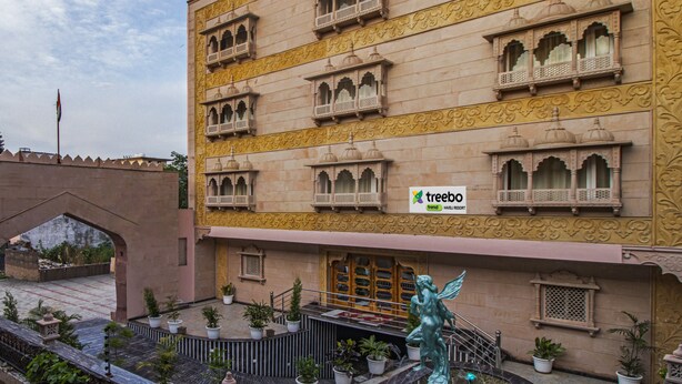 Un edificio de varios pisos con balcones ornamentados y un cartel que indica Treebo Trend Haveli Resort.