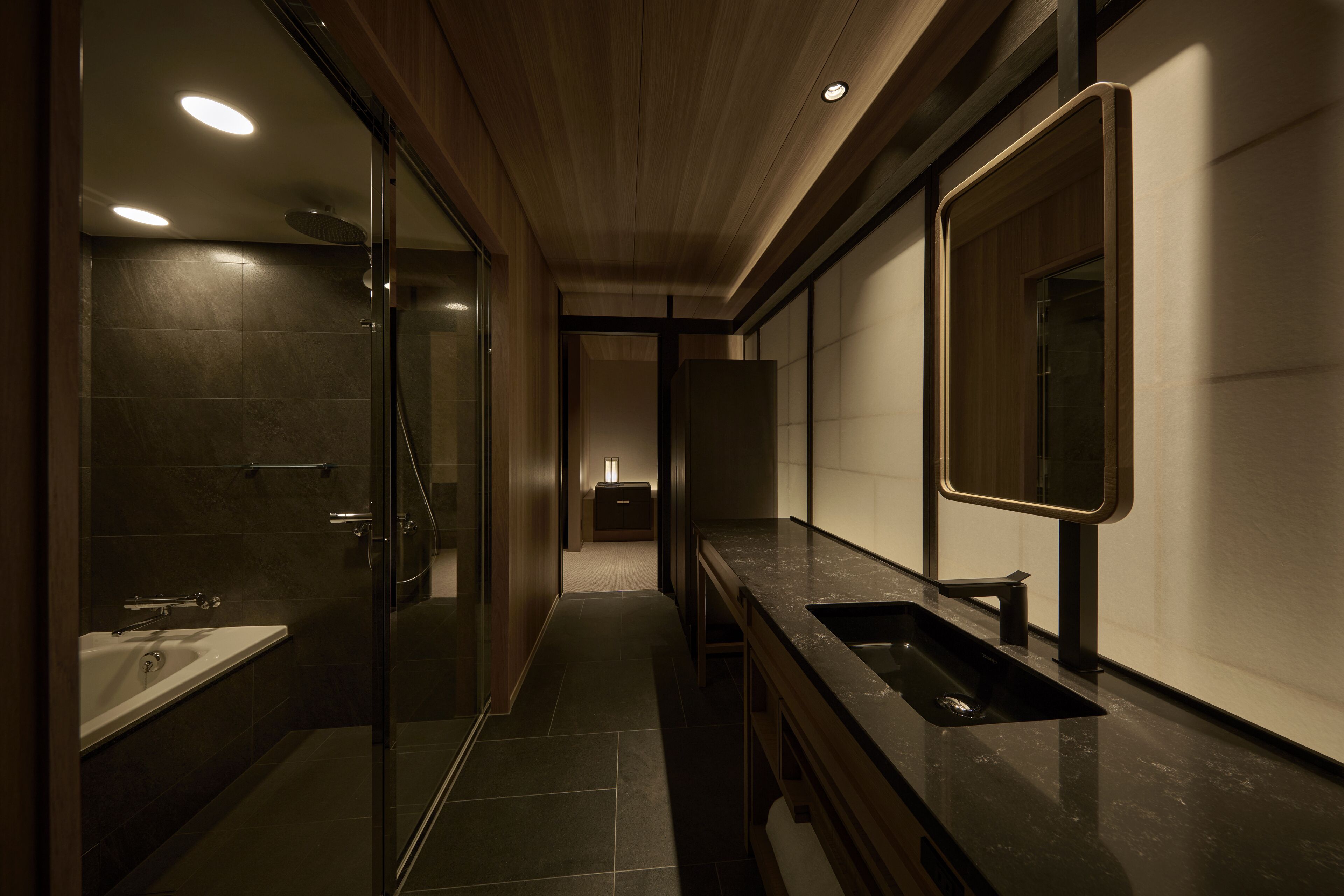 A modern bathroom with a glass shower enclosure, a vanity with a sink, and a large mirror.