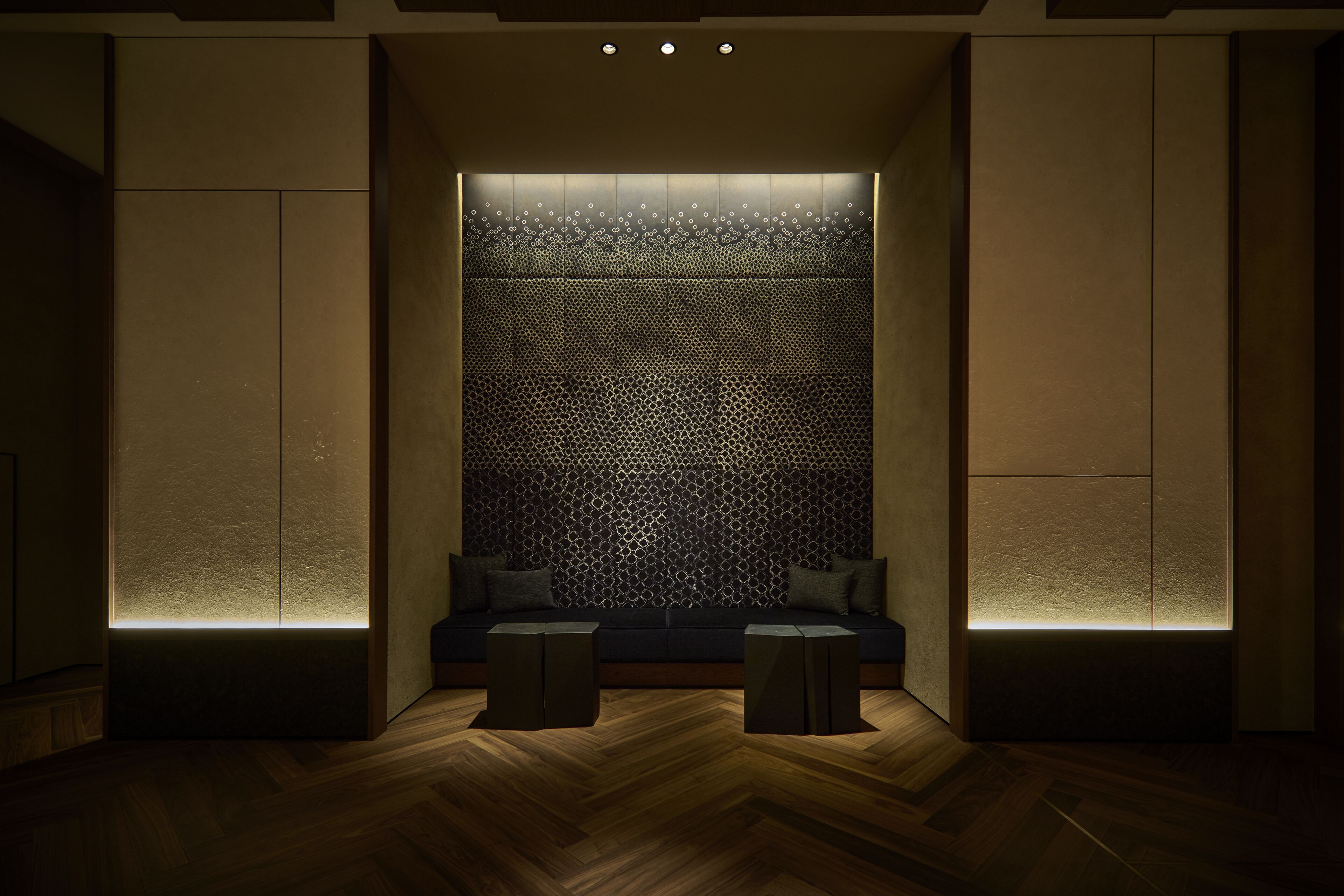 A modern room with a patterned wall, a sofa, and two small tables.